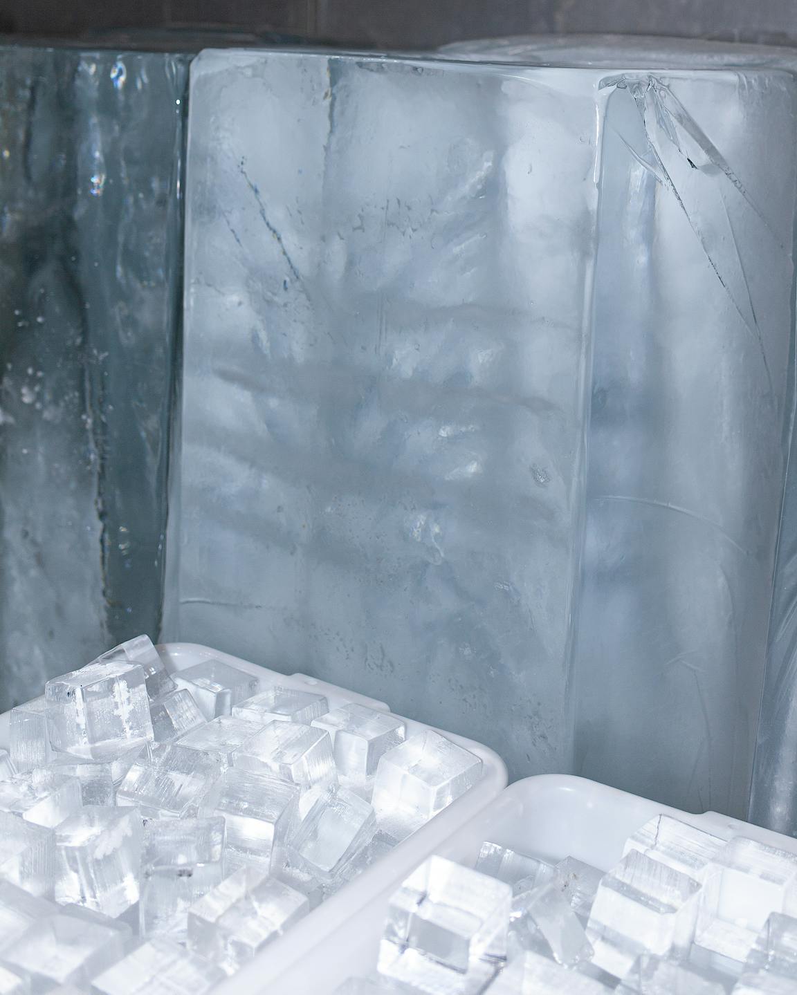 Large blocks of ice stand behind tubs filled with smaller ice cubes.